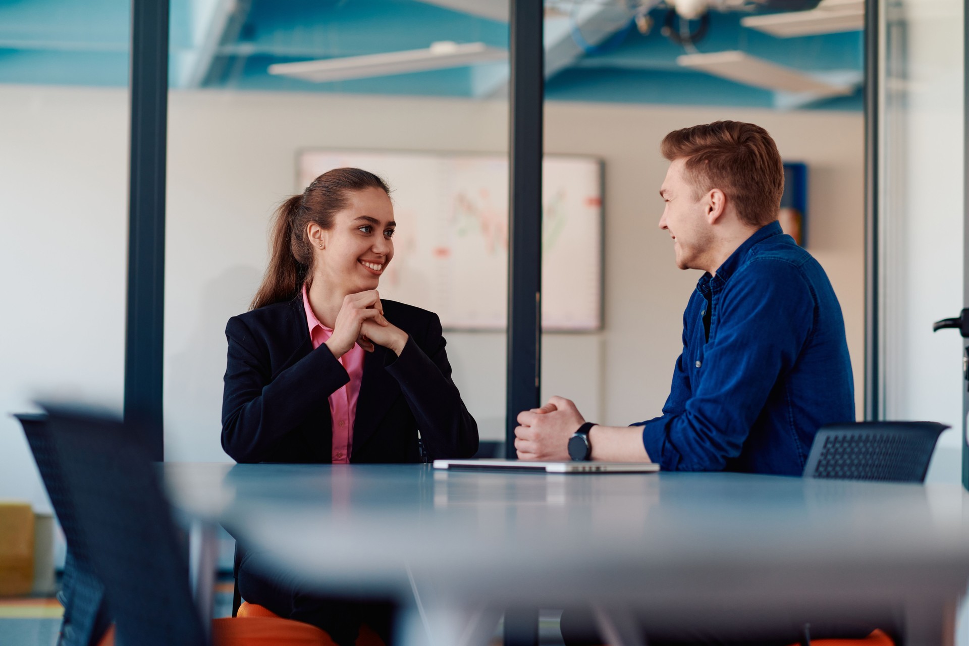 A business leader in a suit conversing with her worker in the IT industry about new business projects and existing business problems