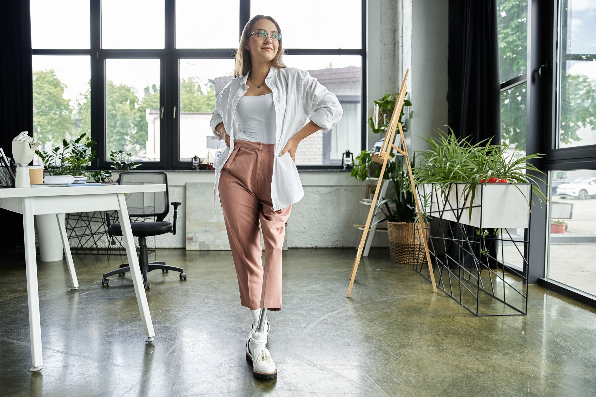 Young woman with prosthetic leg confidently poses in bright office environment